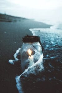 candle in jar on shoreline